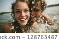Happy Young Couple Splashing in Lake Water on Sunny Day 128763487