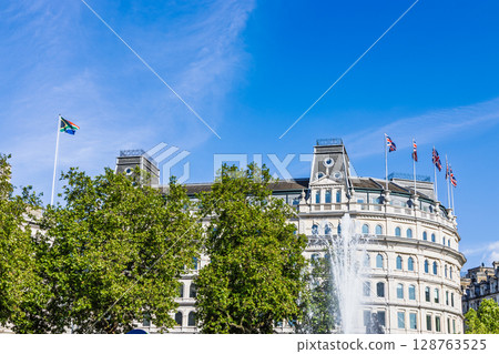 Cityscape with Ornate Building Facade, Flying Flags, Fountain and Lush Greenery. London, UK 128763525
