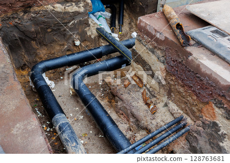 New modern insulated urban pipeline installation construction site  exposed underground pipes in shored trenches. Insulated steel pipes lie connection engineering infrastructure upgrade work 128763681