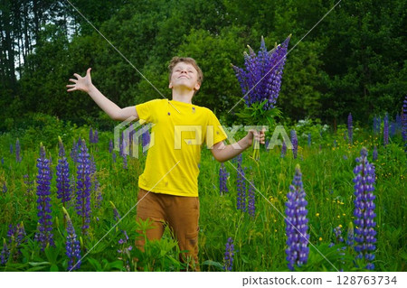 The scene shows a boy in yellow, happily exploring a colorful field of lupines. The scene shows a boy in yellow, happily exploring a colorful field of lupines. 128763734