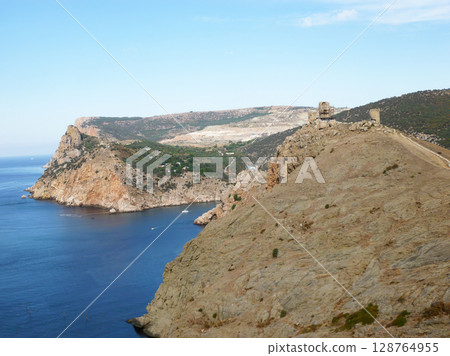 A rocky cliff overlooking the ocean. 128764955