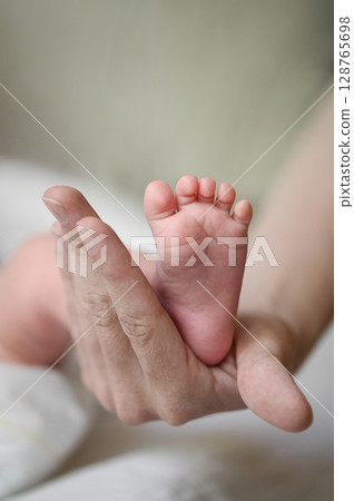 Parent Holding Newborn Baby Feet with Gentle Hands Parent Holding Newborn Baby Feet with Gentle Hands 128765698