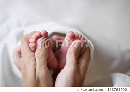 Parent Holding Newborn Baby Feet with Gentle Hands Parent Holding Newborn Baby Feet with Gentle Hands 128765700