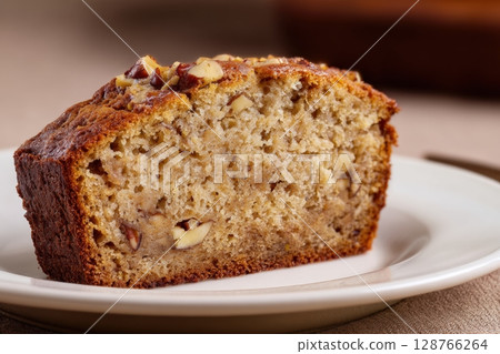 Vegan Banana Bread Slice with Nuts on White Plate, Brown Background 128766264