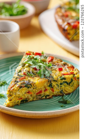 Vegan Vegetable Frittata Slice with Herbs on Pastel Yellow Background 128766265