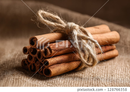 Rustic Cinnamon Sticks Tied with Twine on Pastel Brown Background 128766358