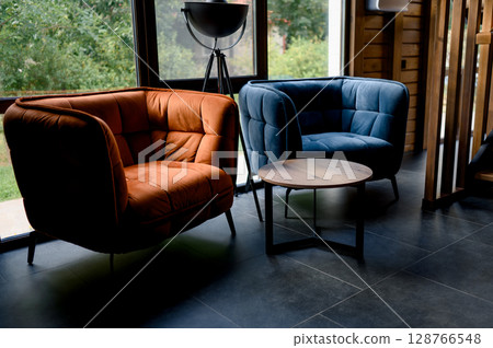 Interior with orange and blue leather chairs and a wooden table by the window 128766548