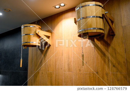 Wooden buckets for dousing with cold water, hanging on the wall 128766579