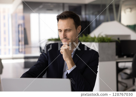 Man looks at laptop with serious, thoughtful expression 128767030