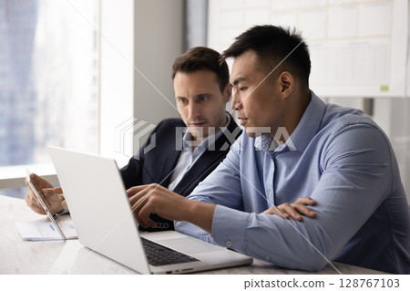 Team engaged in joint task completion using tablet and laptop Team engaged in joint task completion using tablet and laptop 128767103