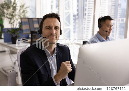 Call center employee equipped with headsets sitting in modern coworking 128767131