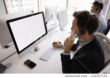 Man wear headset looking at computer with white mockup screen Man wear headset looking at computer with white mockup screen 128767142