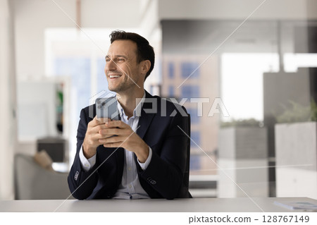 Satisfied businessman sit in workplace with smartphone 128767149