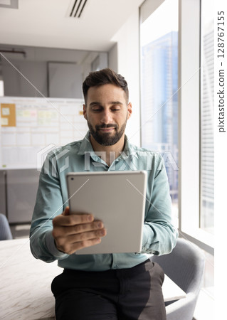 Young businessman working on tablet in modern conference room Young businessman working on tablet in modern conference room 128767155