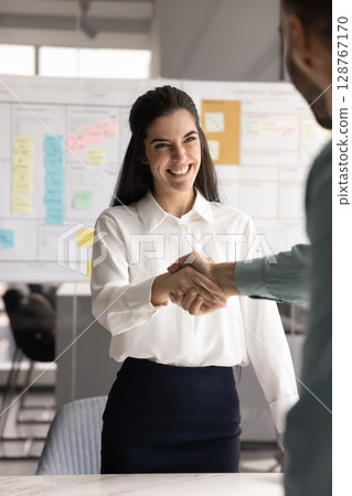 Smiling Latina businesswoman shaking hands with businessman Smiling Latina businesswoman shaking hands with businessman 128767170