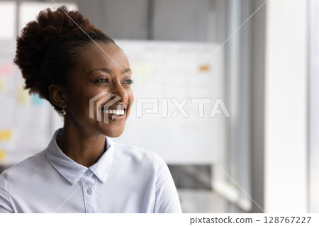 Happy Ethiopian businesswoman looking into distance with smile, copy space Happy Ethiopian businesswoman looking into distance with smile, copy space 128767227