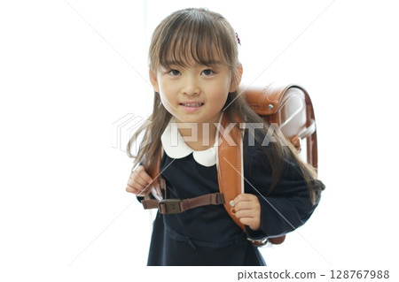 一個一年級的女孩背著書包走路上學 128767988