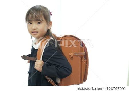 一個一年級的女孩背著書包走路上學 128767991