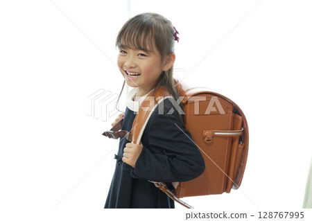 一個一年級的女孩背著書包走路上學 128767995