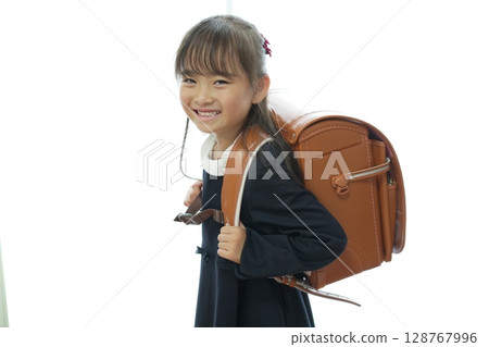 一個一年級的女孩背著書包走路上學 一個一年級的女孩背著書包走路上學 128767996