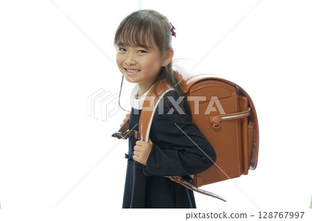一個一年級的女孩背著書包走路上學 一個一年級的女孩背著書包走路上學 128767997