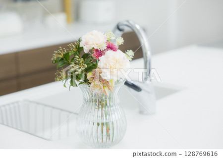 Woman holding a vase in the kitchen Woman holding a vase in the kitchen 128769616