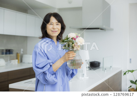 Woman holding a vase in the kitchen 128769617