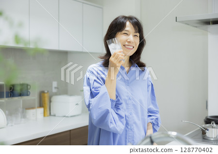 Woman drinking water in the kitchen 128770402