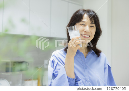 Woman drinking water in the kitchen 128770405