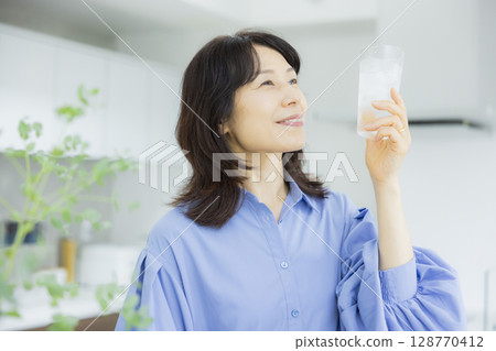 一個女人在廚房喝水 一個女人在廚房喝水 128770412