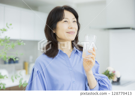 一個女人在廚房喝水 一個女人在廚房喝水 128770413