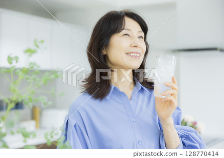 一個女人在廚房喝水 128770414