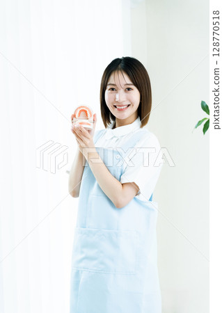 Dental staff woman holding a tooth model 128770518