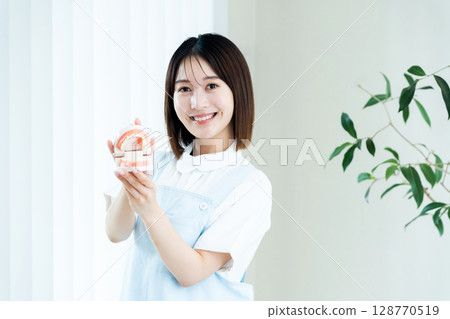 Dental staff woman holding a tooth model 128770519
