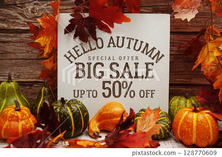 Hello Autumn Big Sale 50% text with maple leaf decoration on wooden background Hello Autumn Big Sale 50% text with maple leaf decoration on wooden background 128770609