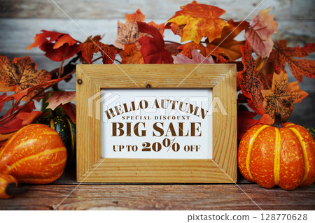 Hello Autumn Big Sale 20% text with maple leaf decoration on wooden background 128770628