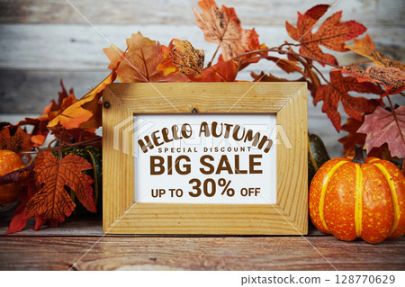 Hello Autumn Big Sale 30% text with maple leaf decoration on wooden background 128770629