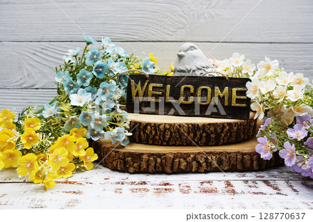 Welcome sign with flower decoration on wooden background 128770637