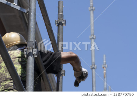 Workers assembling scaffolding Workers assembling scaffolding 128770790