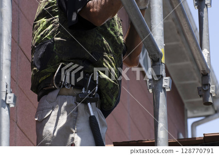 Workers assembling scaffolding 128770791