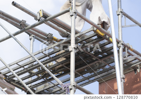 Workers assembling scaffolding 128770810