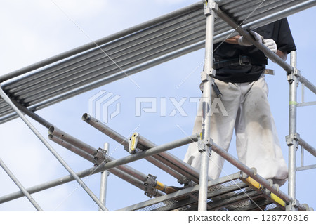 Workers assembling scaffolding Workers assembling scaffolding 128770816