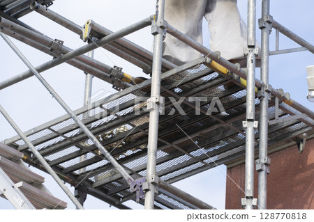 Workers assembling scaffolding Workers assembling scaffolding 128770818