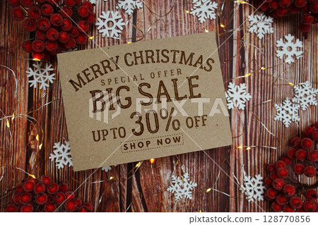 Merry Christmas Big Sale 30% text on paper card with Snowflake and LED light decoration on wooden background Merry Christmas Big Sale 30% text on paper card with Snowflake and LED light decoration on wooden background 128770856