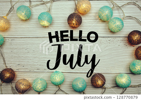 Hello July text with LED cotton balls decorated on wooden background Hello July text with LED cotton balls decorated on wooden background 128770879