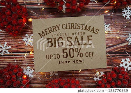 Merry Christmas Big Sale 50% text on paper card with Snowflake and LED light decoration on wooden background 128770889