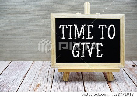 Time To Give text written on chalkboard with easel on wooden background 128771018