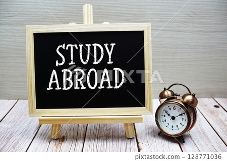 Study Abroad text written on chalkboard with alarm clock on wooden background 128771036