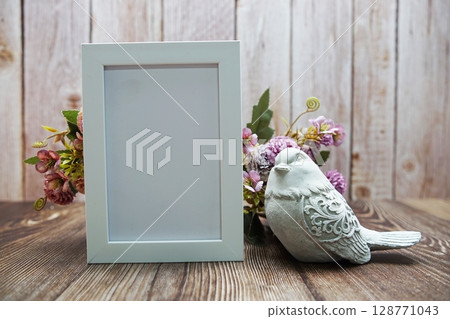 Empty frame decoration with flower bouquet on wooden background 128771043