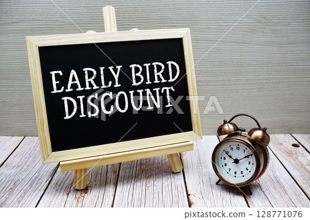 Early Bird Discount text written on chalkboard with alarm clock on wooden background Early Bird Discount text written on chalkboard with alarm clock on wooden background 128771076
